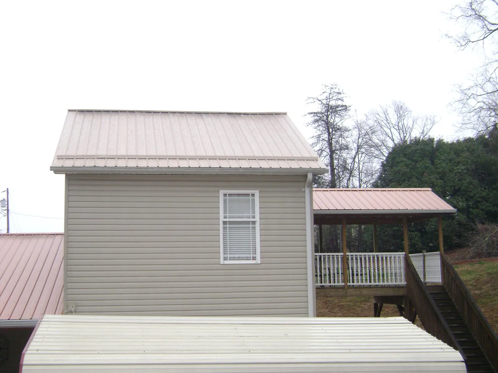 Tan metal roofs on a two story addition and attached porch, from a Roof Replacement job in Stanton